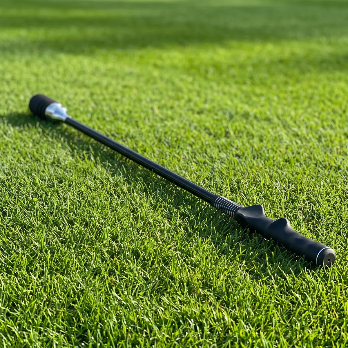 Black Tempo Swing Stick lying on a sunlit golf fairway