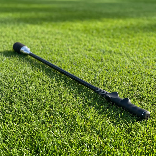 Black Tempo Swing Stick lying on a sunlit golf fairway