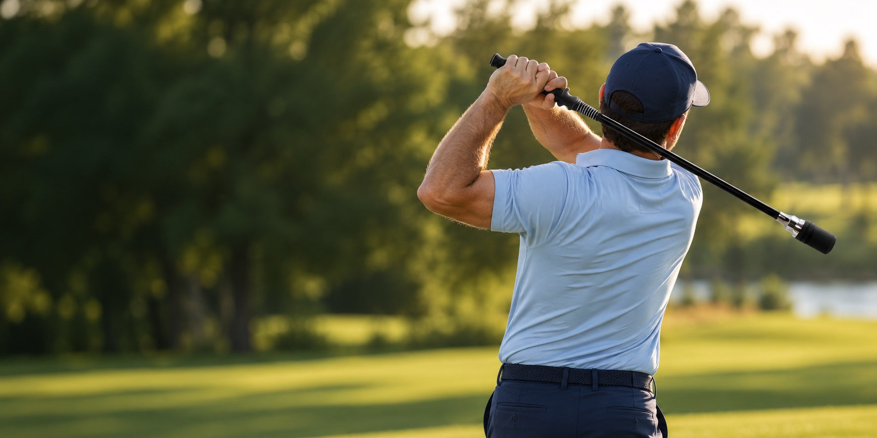 Golfer rehearsing a swing with a tempo training stick on a sunlit course
