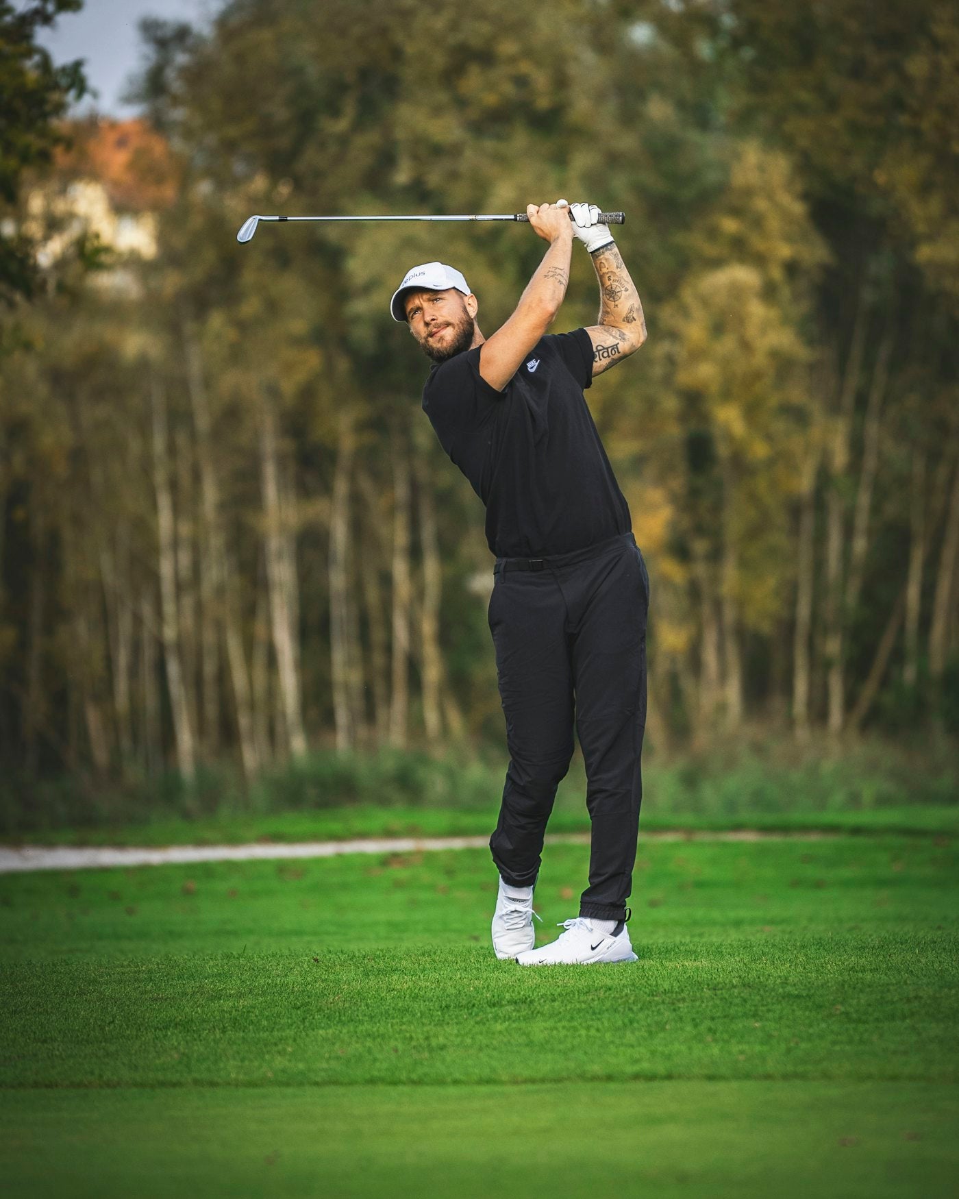 Golfer finishing a swing on a tree-lined course